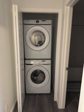Ett tvättrum med två tvättmaskiner placerade ovanpå varandra.