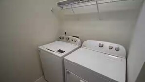 Uma lavanderia com duas máquinas de lavar brancas e um varal.