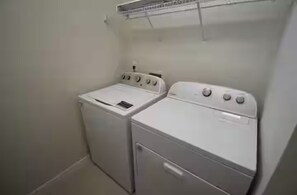 Ein Waschraum mit zwei weißen Waschmaschinen und einem Wäscheständer.