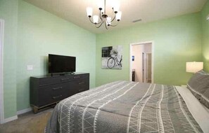 Una camera da letto con un letto, una cassettiera, un televisore e un'opera d'arte a tema bicicletta sulla parete.