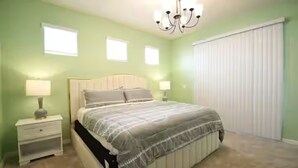 Quarto com cama, mesas de cabeceira, um lustre e uma janela.