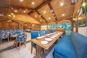 Un restaurante con vigas de madera en el techo, asientos tapizados en azul y una larga mesa de comedor dispuesta para una comida.
