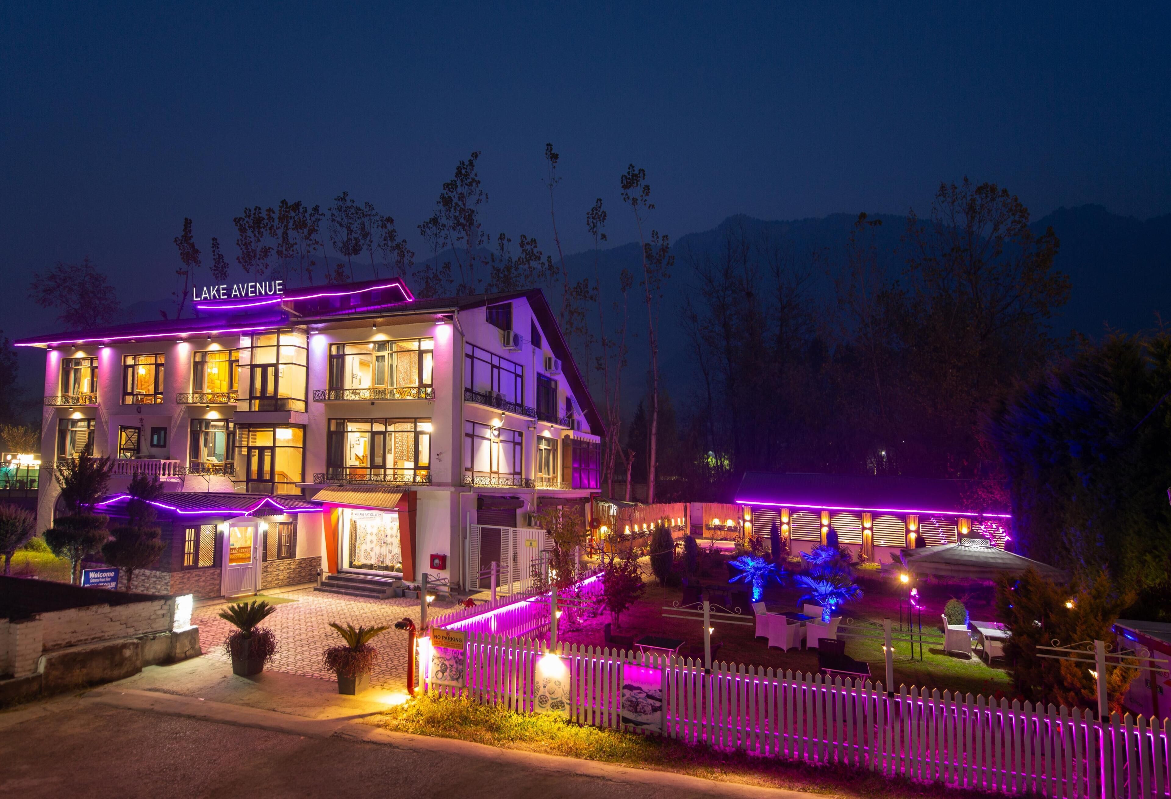 A multi-story hotel with a 'Lake Avenue' sign, a white picket fence, and outdoor seating area.