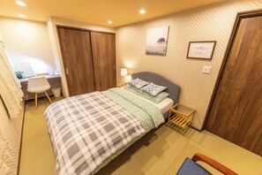 Ein Schlafzimmer mit Bett, Nachttisch, Lampe und Schreibtisch mit Stuhl.