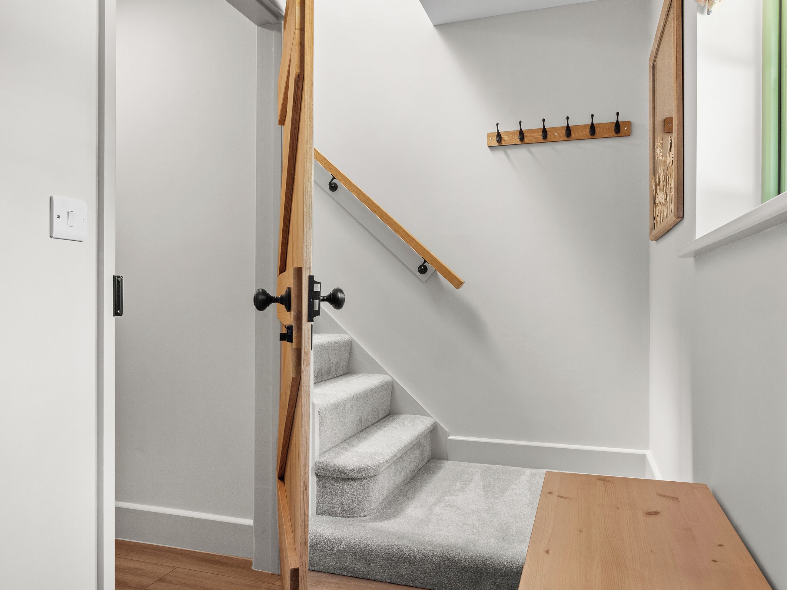 A staircase with a wooden handrail and a grey carpeted landing.
