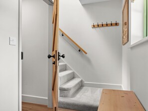 Un escalier avec une rampe en bois et un palier recouvert d’une moquette grise.
