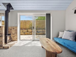 Una sala de estar moderna con chimenea de piedra, un sofá azul y un banco de madera.
