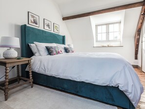 A bedroom with a bed, a bedside table, a lamp, and a window with blinds. - Solstice Stables - UKC9940 (Dorset, Weymouth, Osmington)