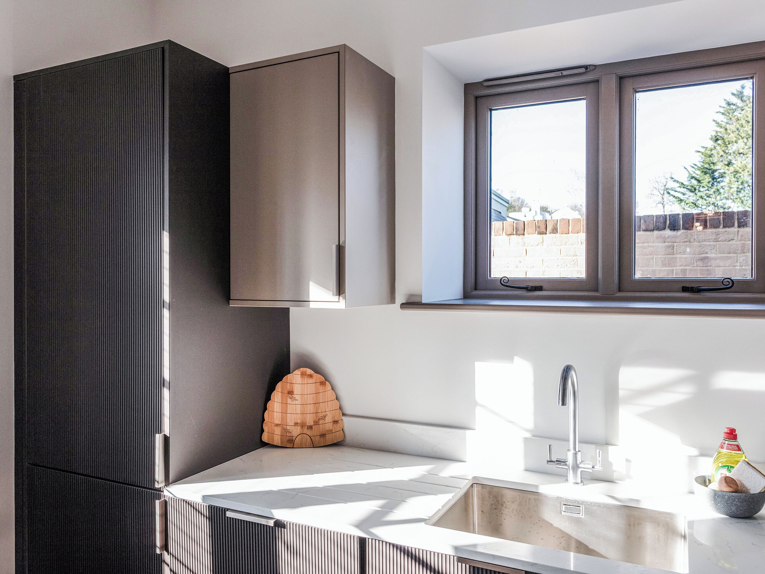 A modern kitchen with a built-in sink, a window with a view of the outside, and a decorative wooden object on the countertop.
