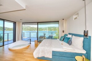 A bedroom with a large bed, a view of the sea, and a balcony with outdoor furniture. - Villa Ronia: An elegant and modern four-story villa located right on the Lake Maggiore, with Free WI-FI. (Angera)