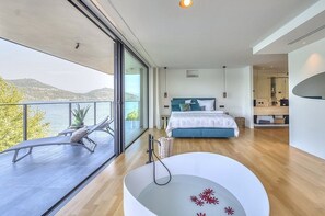 A modern bedroom with a large bed, a bathtub, and a balcony overlooking a body of water. - Villa Ronia: An elegant and modern four-story villa located right on the Lake Maggiore, with Free WI-FI. (Angera)