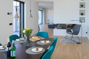 A modern dining area with a dark wooden table, teal chairs, and a vase with yellow flowers. - Villa Ronia: An elegant and modern four-story villa located right on the Lake Maggiore, with Free WI-FI. (Angera)