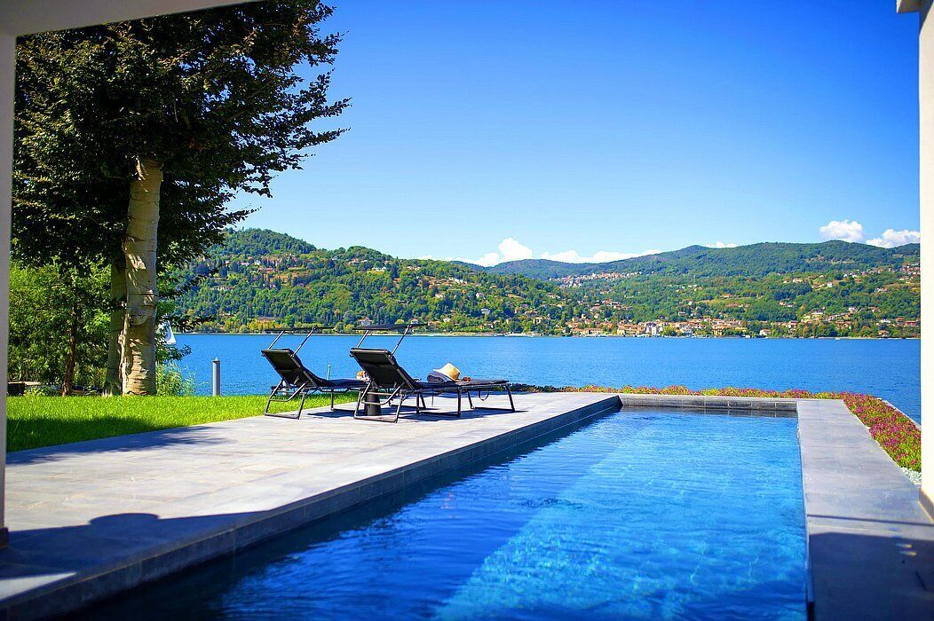 A swimming pool with lounge chairs and a view of a lake and hills.