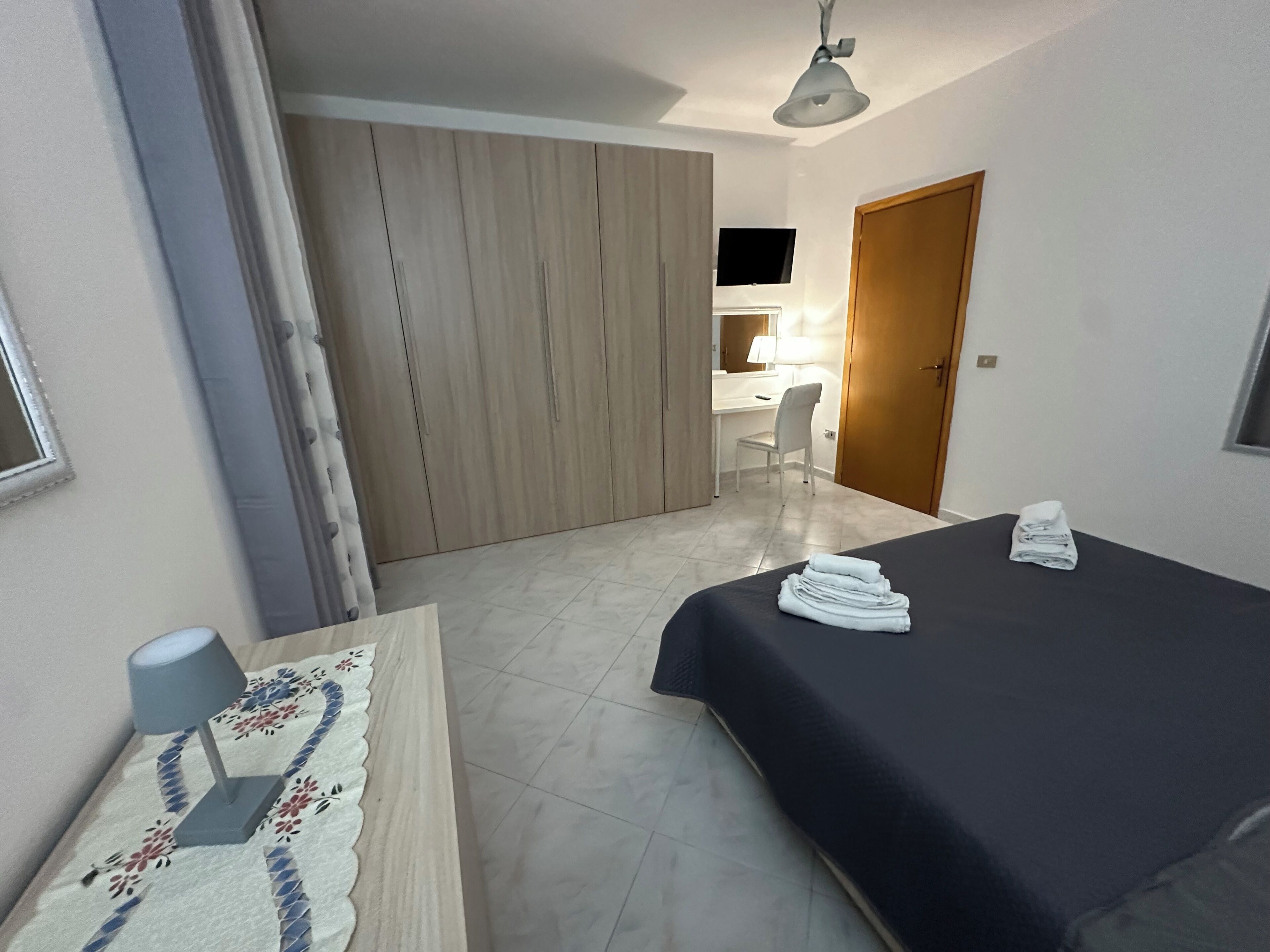 A hotel room with a bed, a desk, a chair, and a wardrobe.