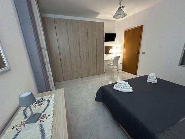 Una habitación de hotel con cama, escritorio, silla y armario.