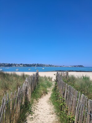 A sandy beach path leading to a beach with boats and houses in the background. - Family-friendly vacation rental for 6–7 people • Nearby greenway •15 min from Morlaix and Huelgoat  (Plougonven)
