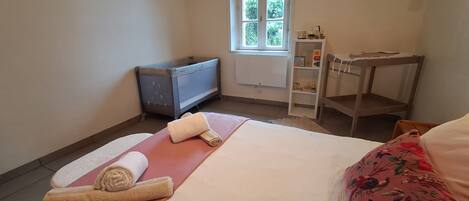 A bedroom with a bed, a small table, a radiator, and a window.