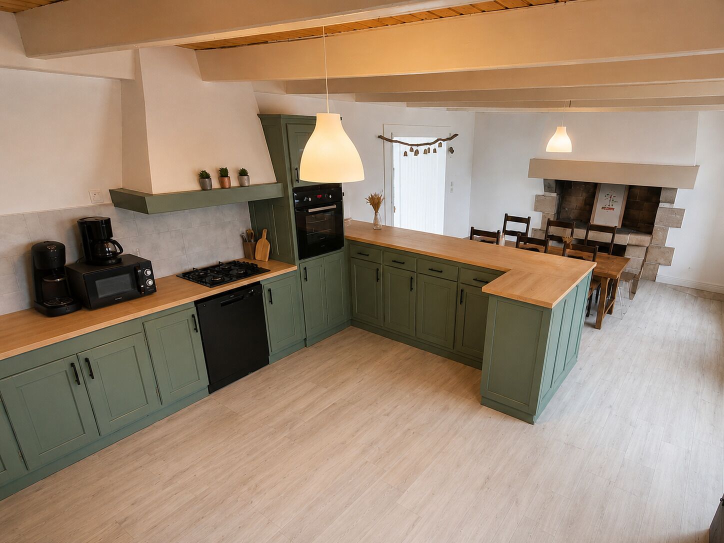 A modern kitchen with green cabinets, a wooden countertop, a built-in oven, and pendant lighting.