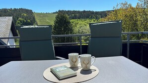 A balcony with a table, two chairs, and three cups with a deer pattern.