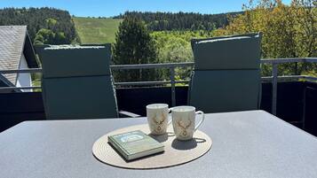 Ein Balkon mit Tisch, zwei Stühlen und drei Tassen mit Reh-Motiv.
