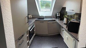 A compact kitchen with a built-in oven, a sink, and a coffee maker.