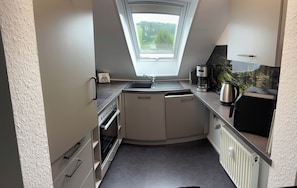 A compact kitchen with a built-in oven, a sink, and a coffee maker.