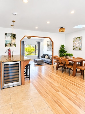 A modern living space with a kitchen area, dining table, and a sofa set. - Canyon View Home, 10 Min to Zoo, Beach & Downtown (San Diego)