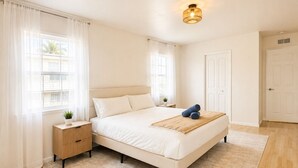 Ein Schlafzimmer mit einem großen Bett, einem Nachttisch, einer Wandleuchte und einer Tür.