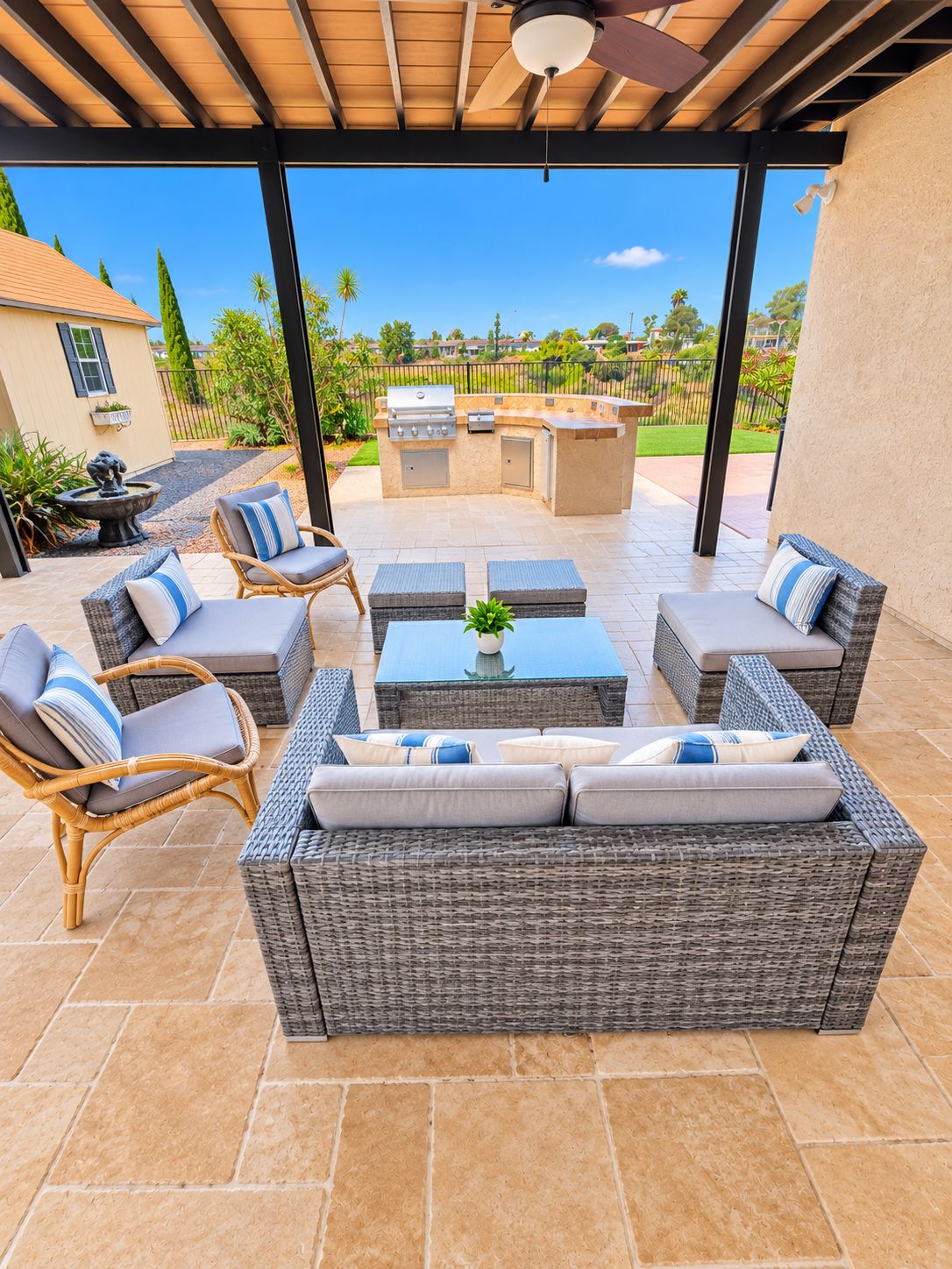 An outdoor patio with wicker furniture, a grill, and a view of the neighborhood.