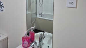 A bathroom with a large mirror, a sink, a shower, and a toilet. - Room-cozy Guest Room With Modern Ameniti (Tipton)