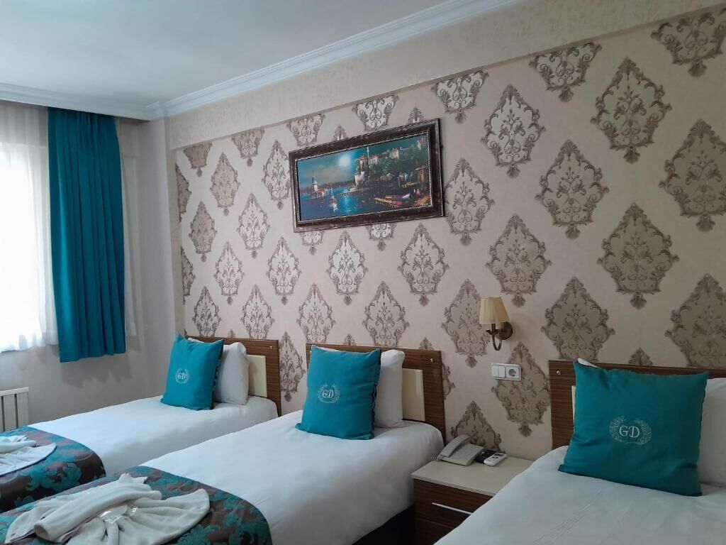 Een hotelkamer met twee bedden, een nachtkastje, een lamp en een lijst aan de muur.