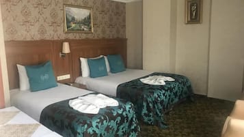 Una habitación de hotel con dos camas, cabecera, lámpara, un cuadro y suelo alfombrado.