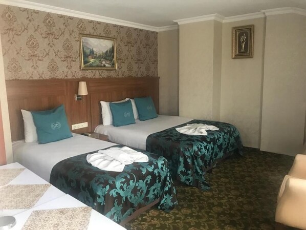 A hotel room with two beds, a headboard, a lamp, a painting, and a carpeted floor.
