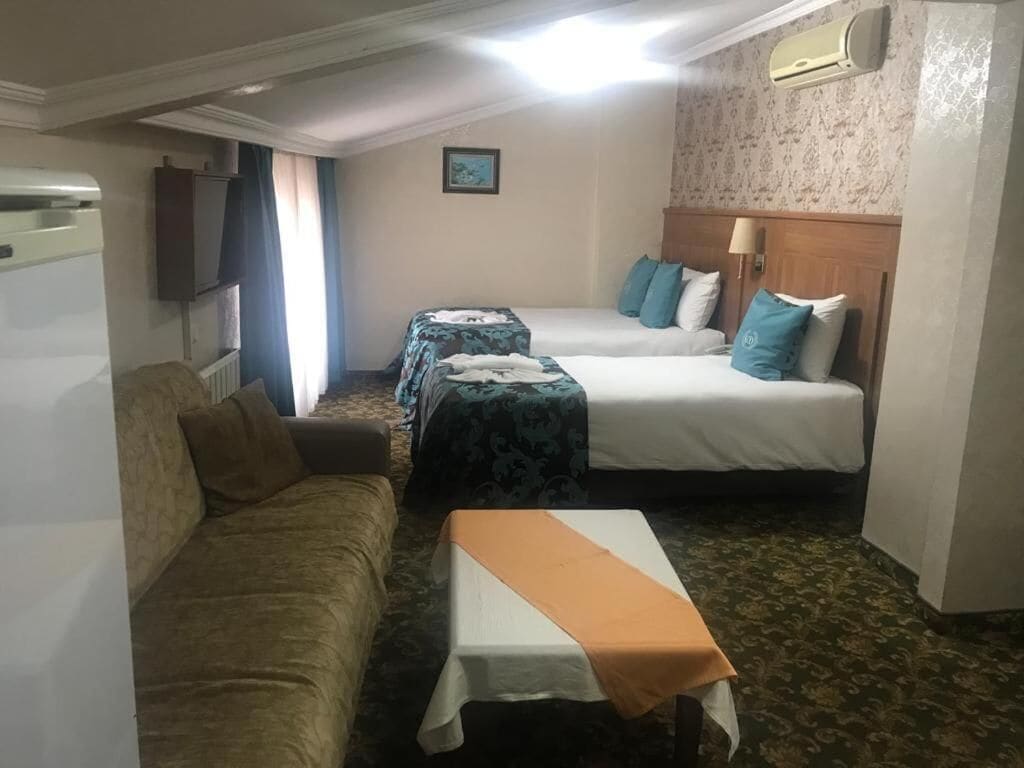 Habitación de hotel con dos camas, un sofá, una mesa y un televisor.