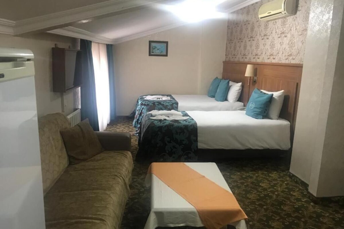 Habitación de hotel con dos camas, un sofá, una mesa y un televisor.