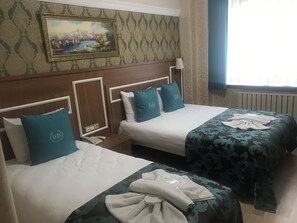 Habitación de hotel con dos camas, un cuadro en la pared, un teléfono en la mesita de noche y una ventana con cortinas.