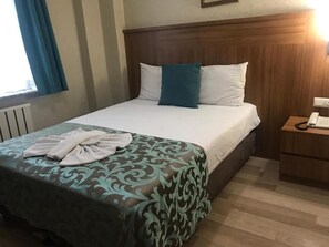 A hotel room with a bed, a bedside table with a phone, and a window with curtains. - GRAND DİLARA HOTEL (Istanbul)