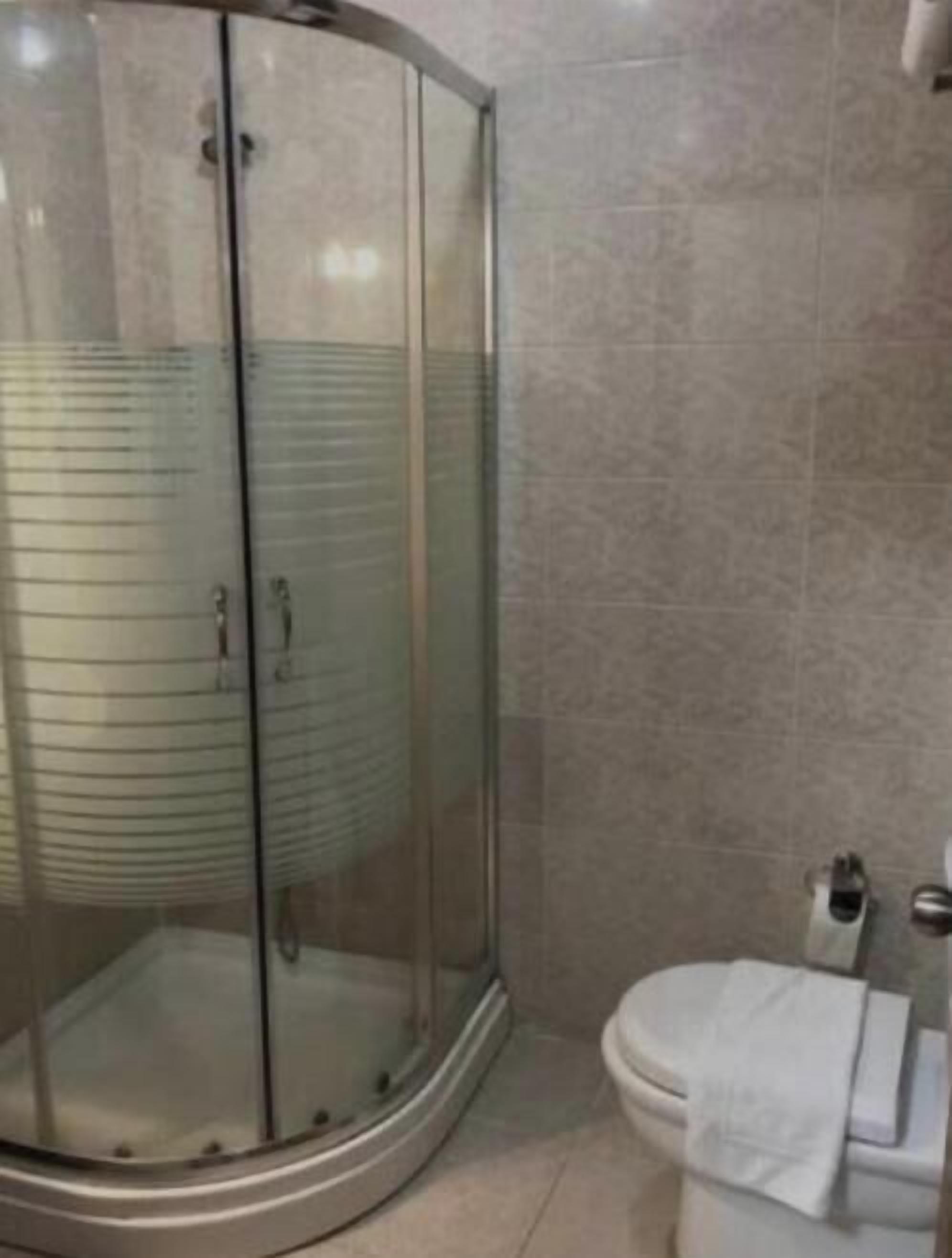 Un baño con ducha de vidrio, inodoro y perchero para toallas.