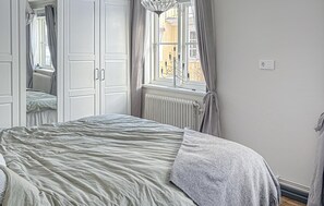 A bedroom with a bed, a radiator, and a window with curtains. - 4 bedroom amazing home in Vaggeryd (Vaggeryd)