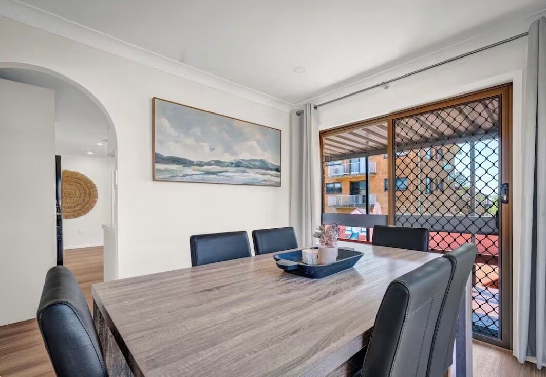 A dining area with a wooden table, chairs, and a view through a glass door.