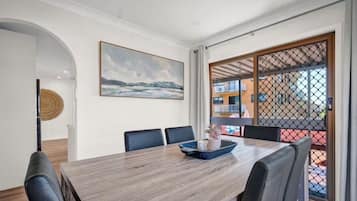 A dining area with a wooden table, chairs, and a view through a glass door.
