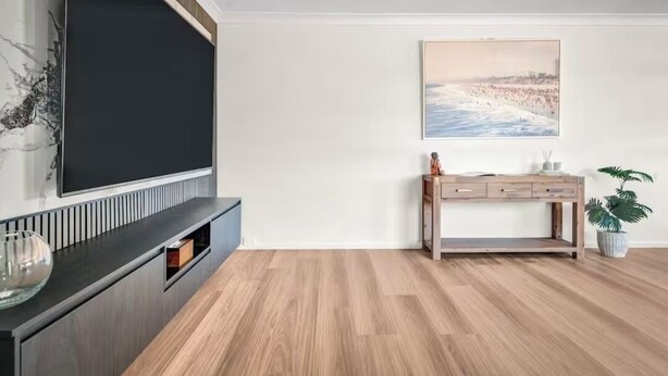Un salon moderne doté d’un téléviseur à écran plat, d’un parquet, d’une console et d’un tableau encadré au mur.