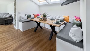 Ein zeitgemäßer Essbereich mit Holztisch, grauen Sitzkissen und Oberlichtern.