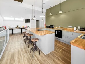 Eine moderne Küche mit Kochinsel, Barhocker und einem Essbereich mit Tisch und Stühlen.