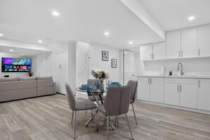 A modern living space with a dining area, a sofa, a TV, and a kitchen. - Luxury 2BR Basement near Wonderland/Vaughan, Wi-Fi (Vaughan)