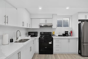 A modern kitchen with white cabinets, stainless steel appliances, and a window above the sink. - Luxury 2BR Basement near Wonderland/Vaughan, Wi-Fi (Vaughan)