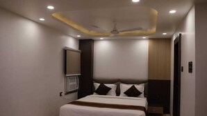 Une chambre d’hôtel équipée d’un lit, d’un ventilateur de plafond, d’un éclairage encastré, d’un téléviseur fixé au mur et d’une porte.