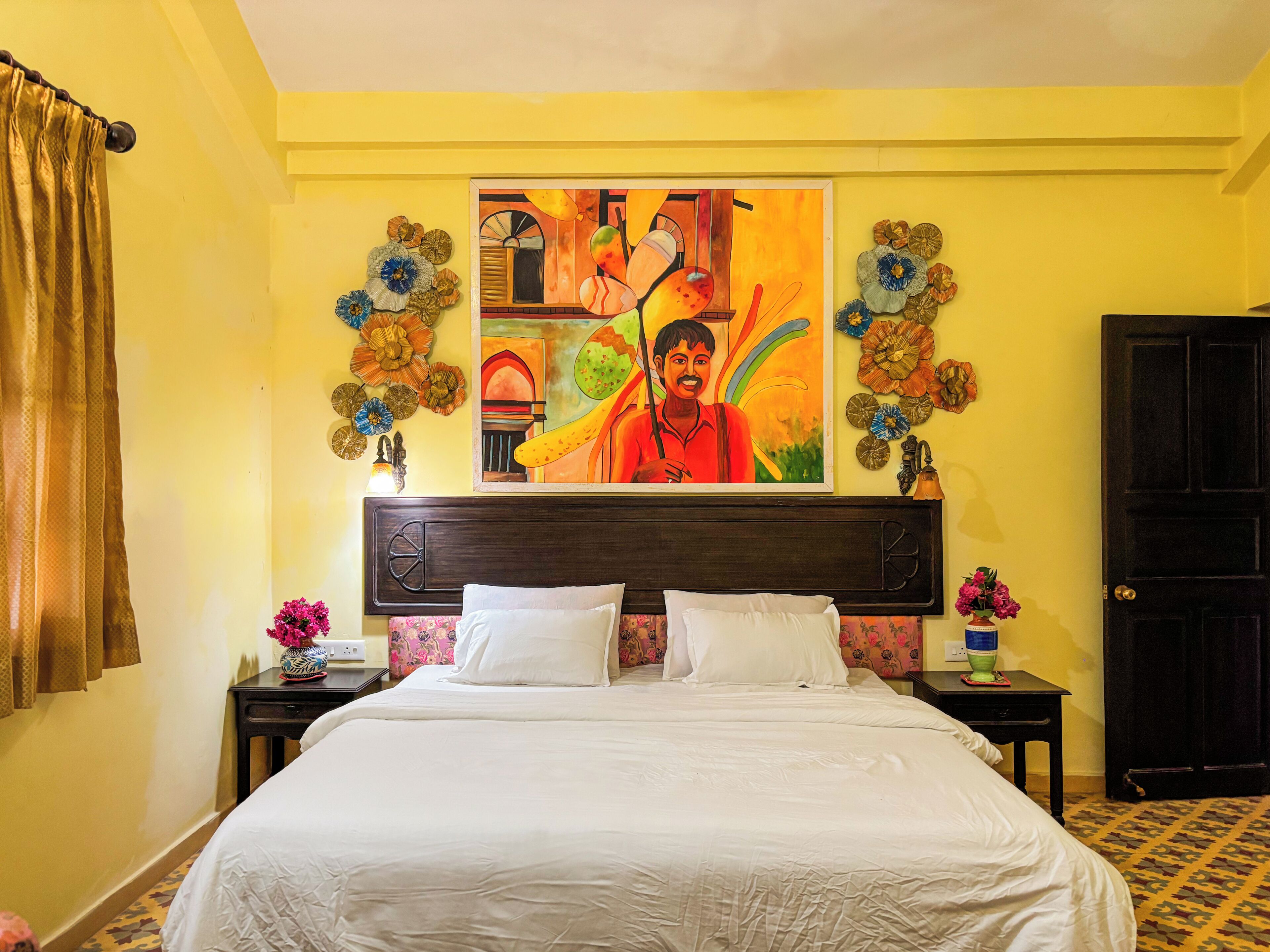 A hotel room with a large bed, a painting on the wall, and decorative wall art.