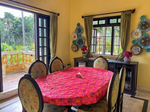 A dining area with a round table, chairs, a vase with flowers, and decorative wall art.