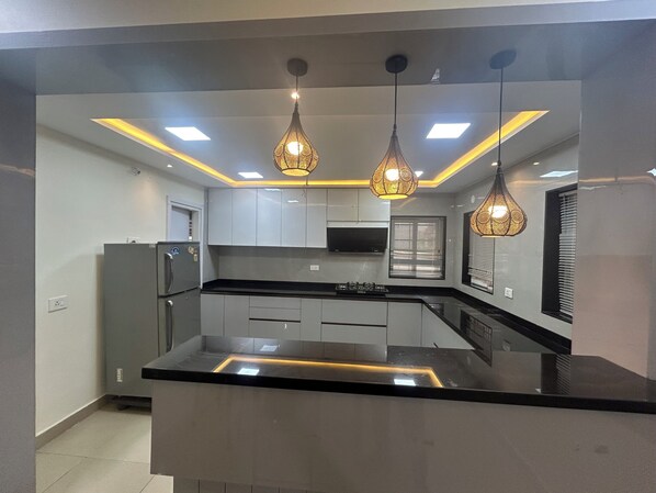 A modern kitchen with a central island, pendant lighting, and built-in appliances.